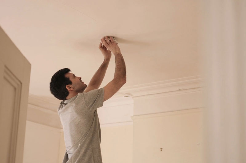 man changing smoke alarm batteries