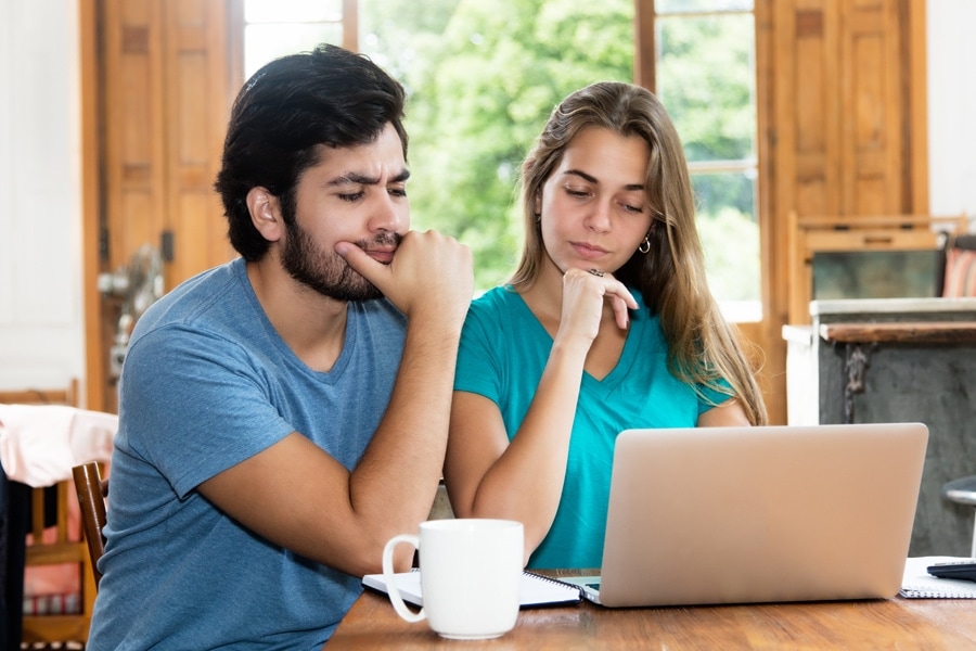 Couple looking at their laptop confused.