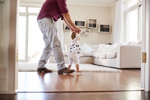 Father helping daughter learn to walk at home